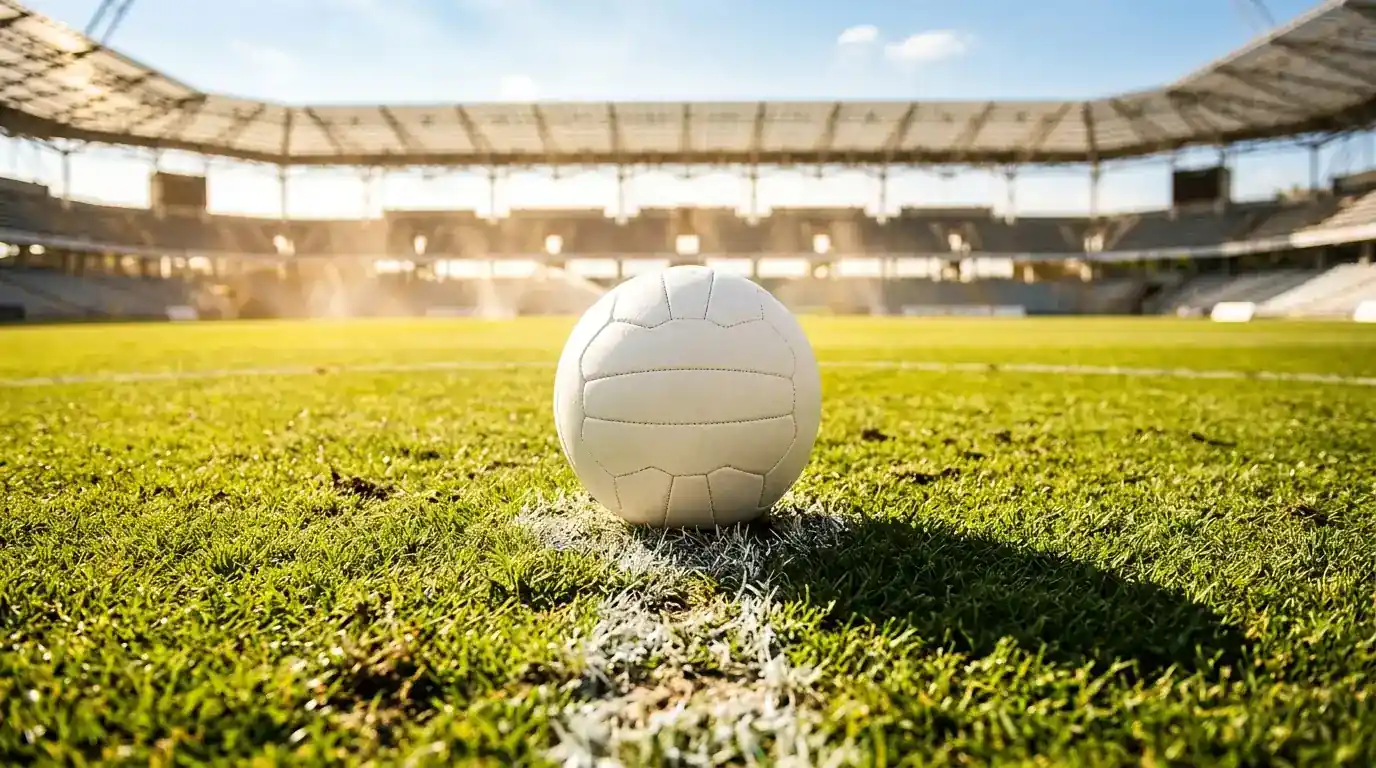 Fussball auf dem Anstosspunkt eines sonnendurchfluteten offenen Stadions bei Hitze
